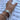 A close-up of a person's hand resting on printed sheet music, wearing a silver chain link bracelet and a small silver ring, with a thin red cord bracelet also visible.