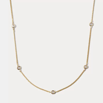 Gold necklace with small diamonds on a light gray background