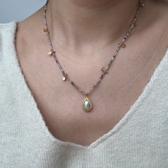 Woman wearing healing tourmaline stone necklace with gold plated silver pendant.