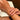 A close-up lifestyle shot of a delicate silver chain bracelet worn on a woman's wrist, with her hands resting on an open book. The nails are manicured with a classic French tip.