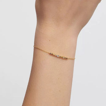 Minimalist gold-plated silver chain bracelet set with small, delicate colorful zircon stones, styled alone on a neutral background.