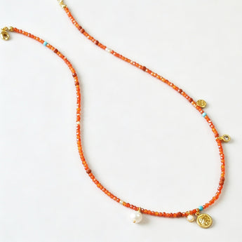Minimalist gold-plated steel necklace featuring a mix of vibrant orange beads, turquoise stones, and elegant pearls, styled on a clean background.