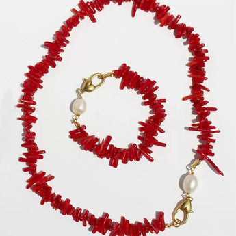 A red coral chip necklace and matching bracelet set with gold-tone clasps and white pearl accents, displayed on a light gray background.