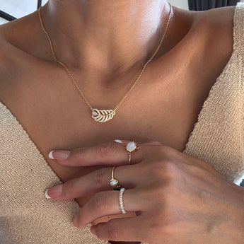 A models the dainty feather necklace with natural opal, showcasing the gold plated Necklace.