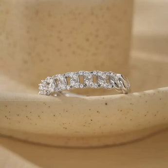 A silver diamond eternity band ring displayed on a speckled beige ceramic dish.