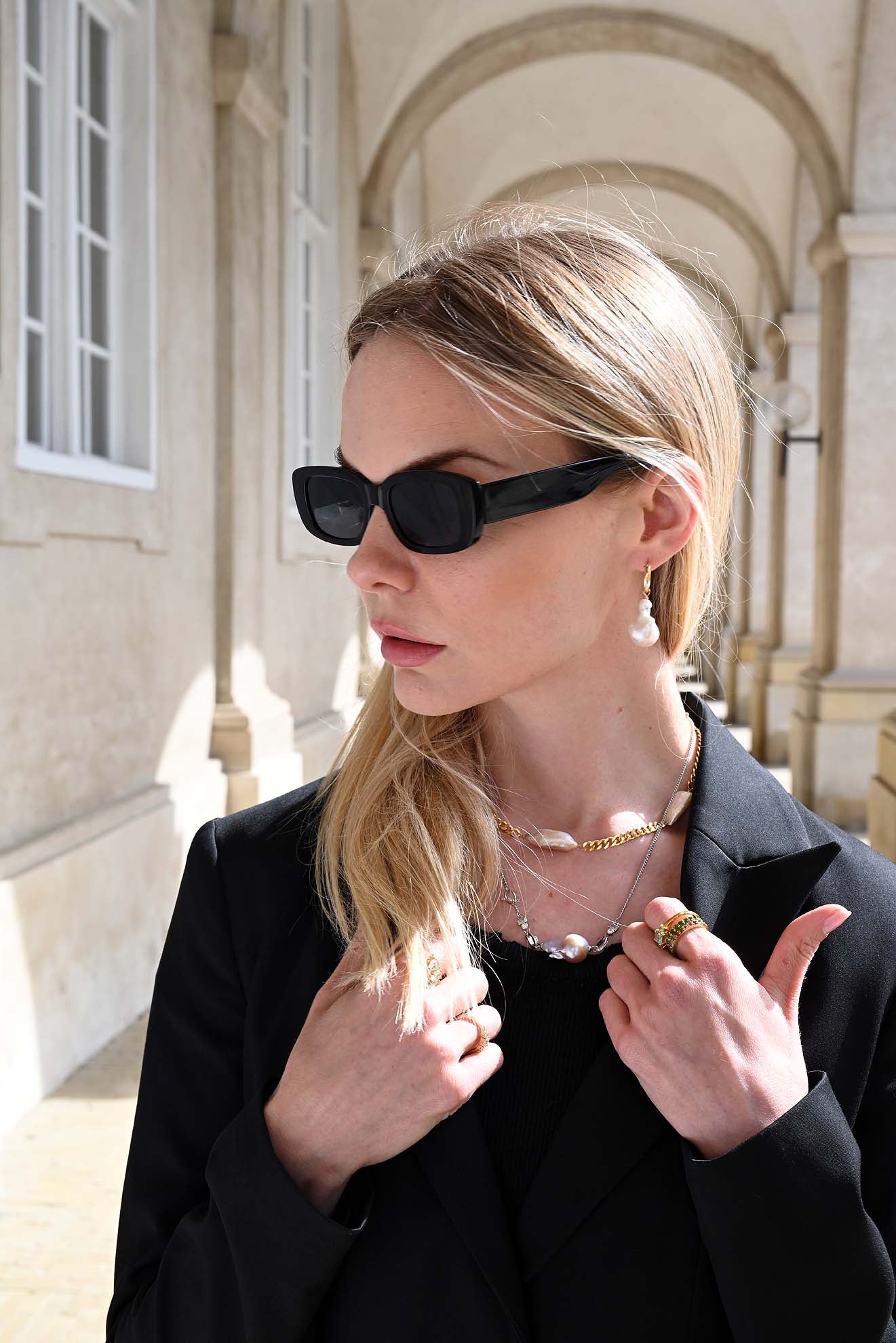 Confident woman wearing a bold Cuban pearl choker necklace, layered with minimalist gold jewelry for a Nordic-inspired statement look
