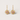Gold earrings with pink gemstones on a light gray background