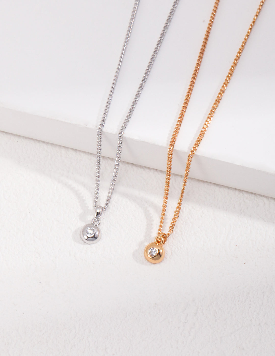 Delicate minimalist zircon pendant necklace on a gold chain, styled in a flat lay for everyday elegance. Features a sparkling round-cut stone with adjustable 40cm+6cm length.