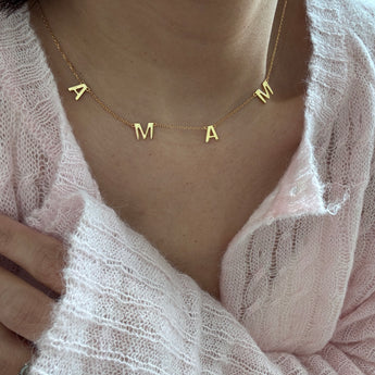 Woman wearing mama letters necklace close to chest mother's day