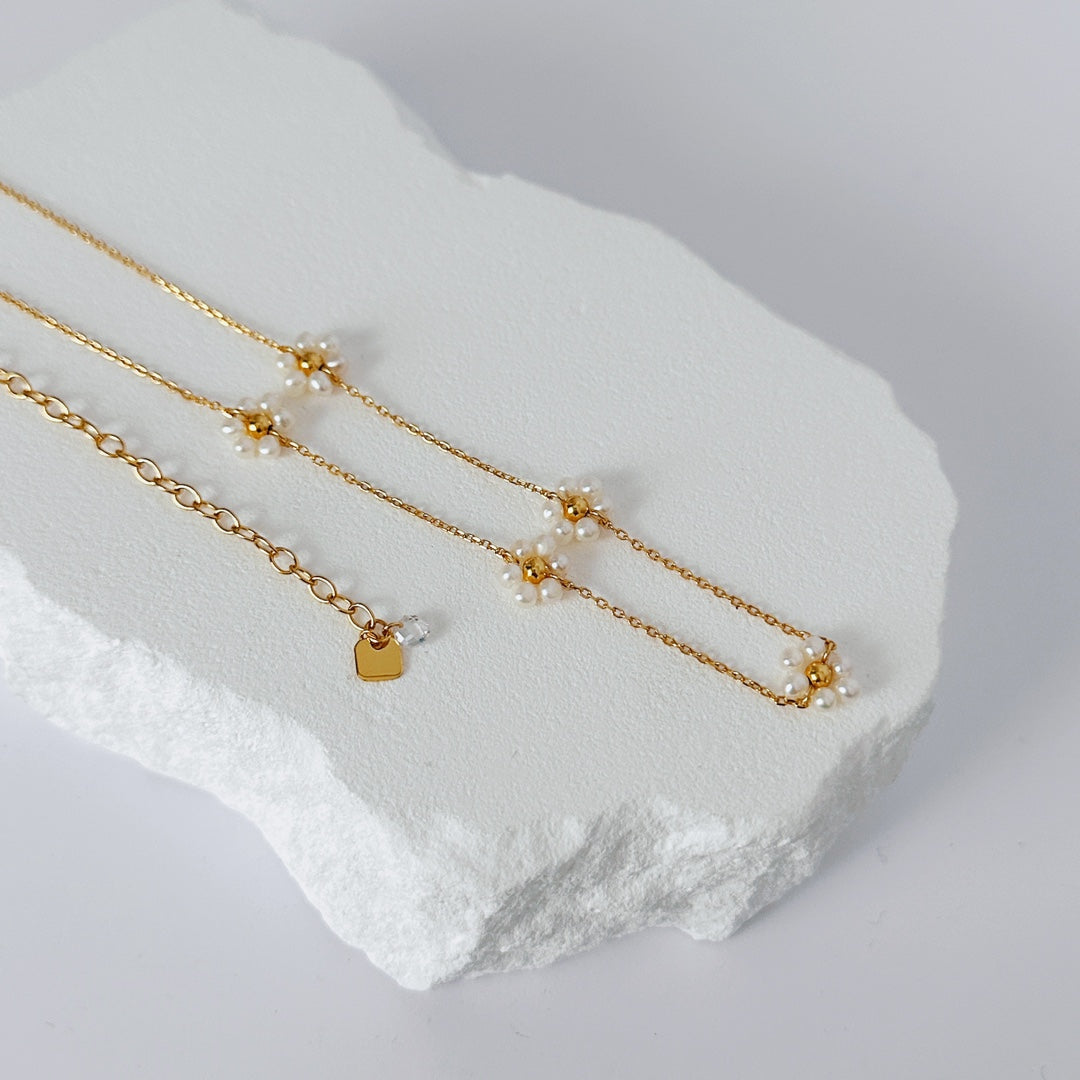 Close-up of handmade sunflower charms with natural pearls on a delicate 18K gold vermeil chain, showing artisan craftsmanship