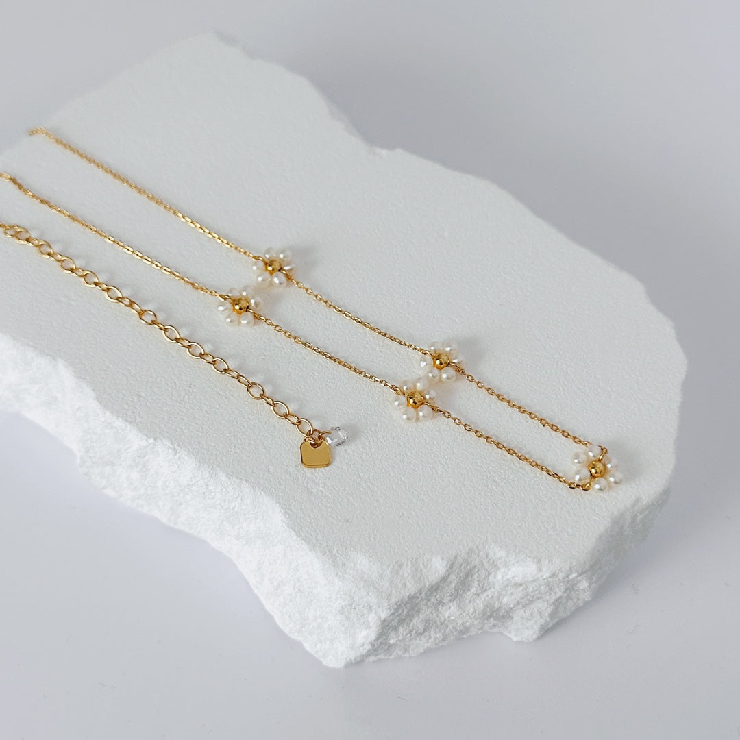 Handmade 18K gold vermeil sunflower necklace with five natural freshwater pearls, layered on a model’s collarbone. Symbol of hope and resilience in delicate jewelry