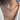 A close-up of a person's neck and chest wearing a delicate beaded necklace with a small gold feather pendant. The necklace features small multicolored beads and gold-toned metal details, worn over a white top.