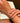 A close-up lifestyle shot of a delicate silver chain bracelet worn on a woman's wrist, with her hands resting on an open book. The nails are manicured with a classic French tip.