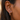 Close-up of an ear wearing a colorful earring with a blurred background