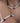 A close-up of a person's neck and arm wearing a matching jewelry set: a pearl necklace and a pearl bracelet, both decorated with small red berry charms and green leaf accents.