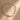 A delicate gold chain bracelet with a large, irregular pearlescent white shell centerpiece, displayed on a textured brown background with soft diagonal shadows.