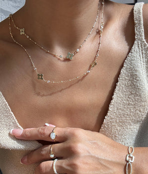 Woman wearing dainty long gold necklace with zircon flower detail.