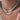 Close-up of a person wearing a layered necklace set: one strand of irregular white pearls and one turquoise beaded chain with small gold spikes and a tiny red bead accent.