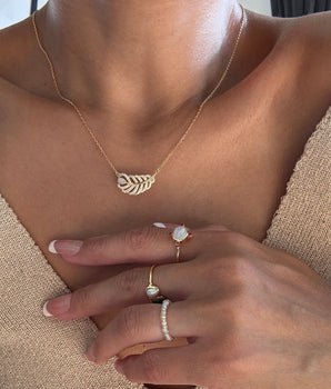 A models the dainty feather necklace with natural opal, showcasing the gold plated Necklace.