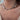 A close-up of a person's neck and chest wearing a delicate necklace made of small dark blue beads with several small gold coin charms and a gold disc accent.