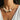 A woman wearing a chunky necklace made of natural sea urchin spines and a large spiral shell, styled with a white sheer V-neck top against a lush green tropical background.