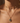 Close-up of a person wearing a gold necklace with a pendant on a neutral background