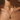 Close-up of a person wearing a gold necklace with a pendant on a neutral background
