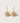 Gold earrings with pink gemstones on a light gray background