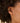 Close-up of an ear wearing a gold hoop earring with hair partially covering the face.