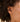 Close-up of an ear wearing a gold hoop earring with hair partially covering the face.