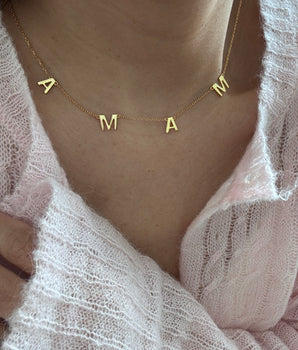 Woman wearing mama letters necklace close to chest mother's day